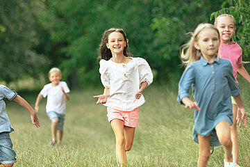 Lachende Kinder laufen auf einer Wiese