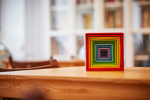 Bunter Holzwürfel zum Stapeln steht auf Tisch im Montessori Klassenzimmer